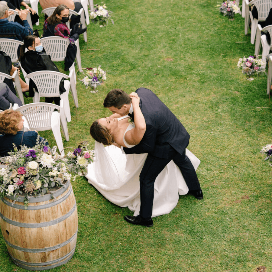A couple shares a romantic dip during their outdoor wedding ceremony.