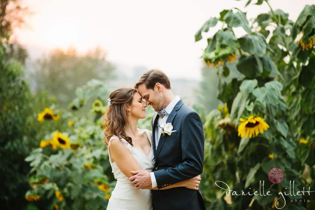 A couple embraces in a sunflower field during golden hour.