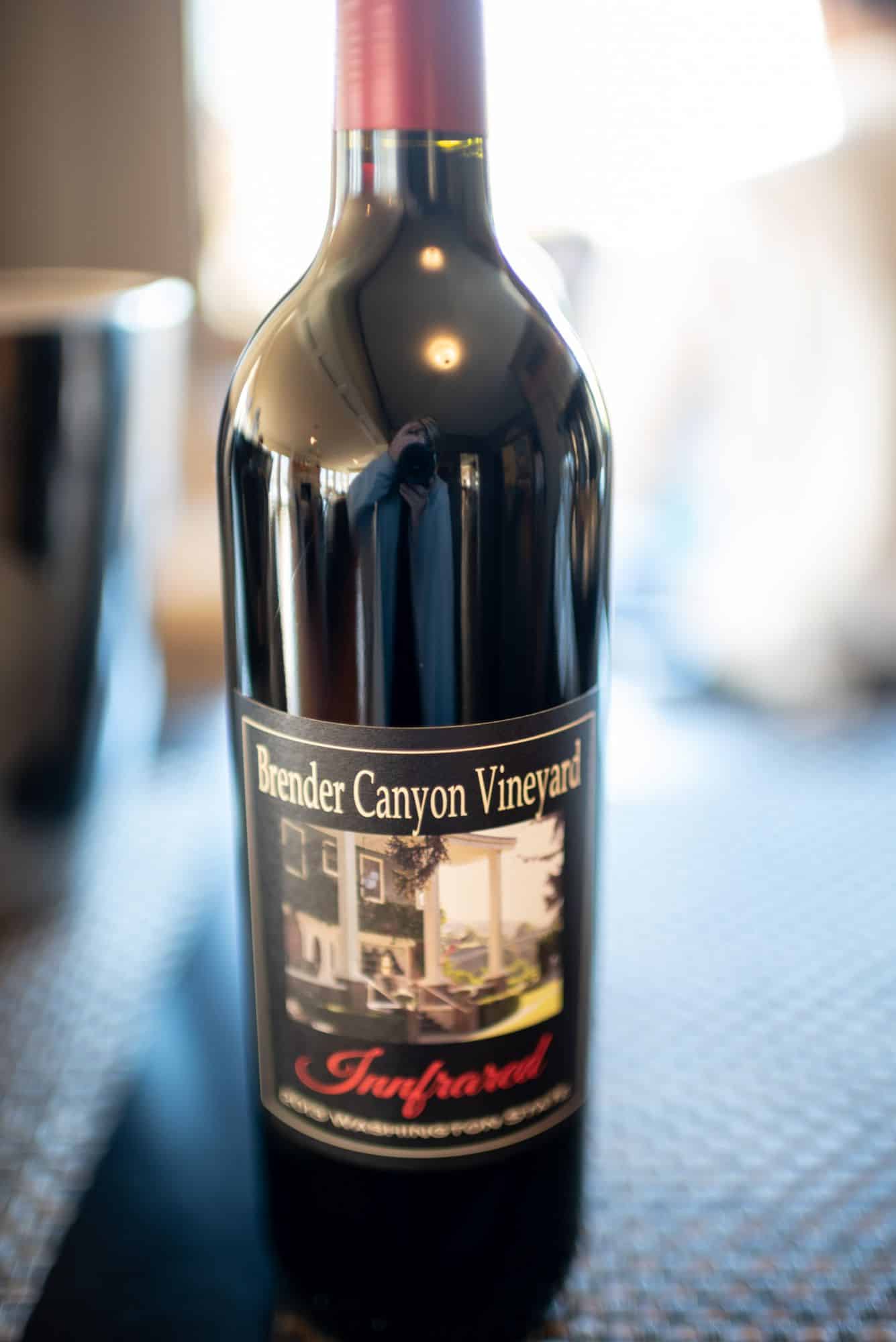 A close-up of a bottle of Brender Canyon Vineyard red wine with a reflective surface.