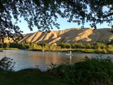 A serene river landscape surrounded by hills and green vegetation.
