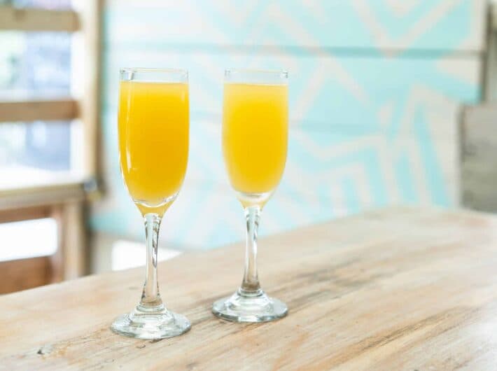 Two glasses of orange juice on a wooden table.