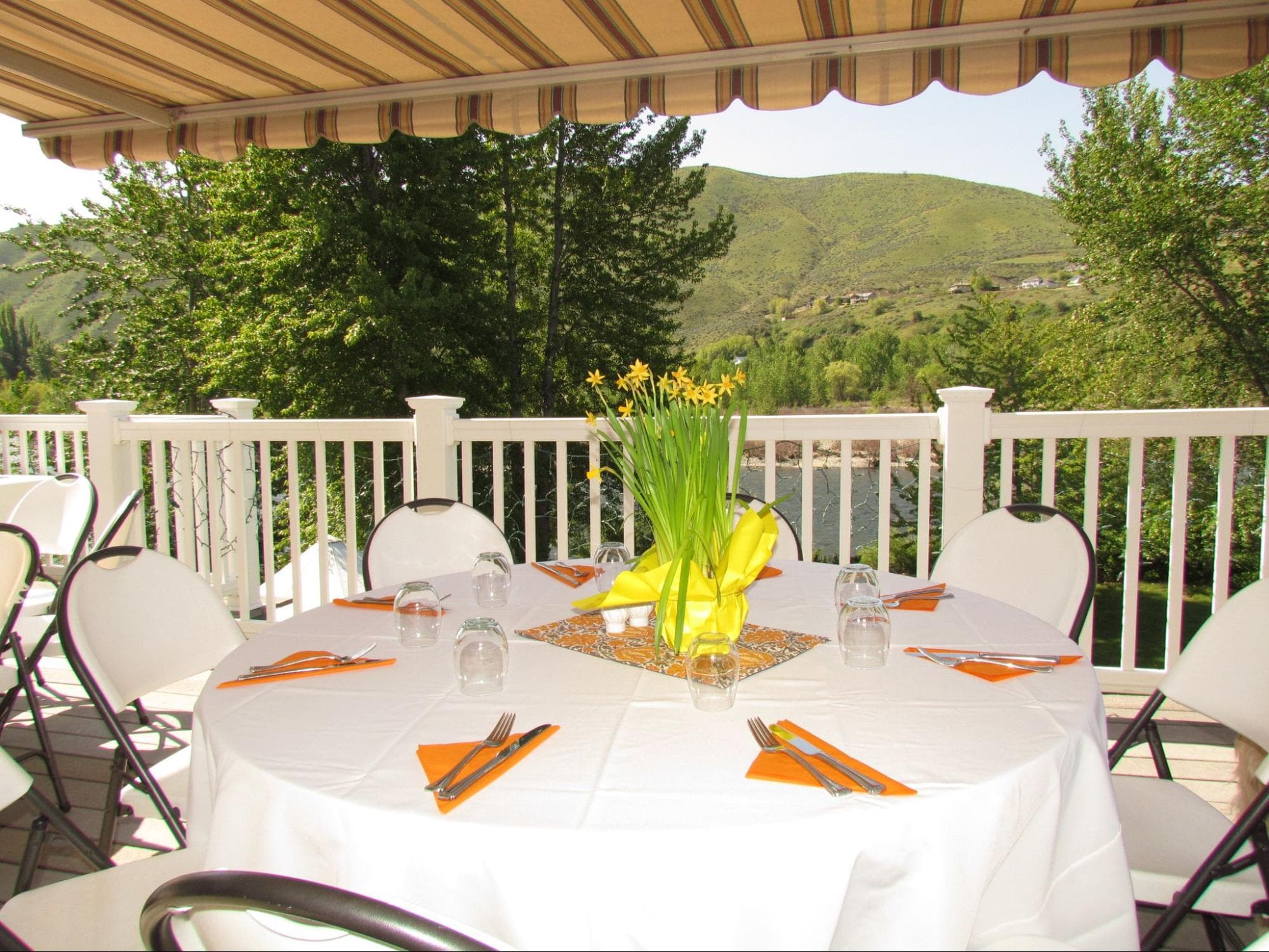 A beautifully arranged outdoor dining table with a floral centerpiece and scenic hills in the background.