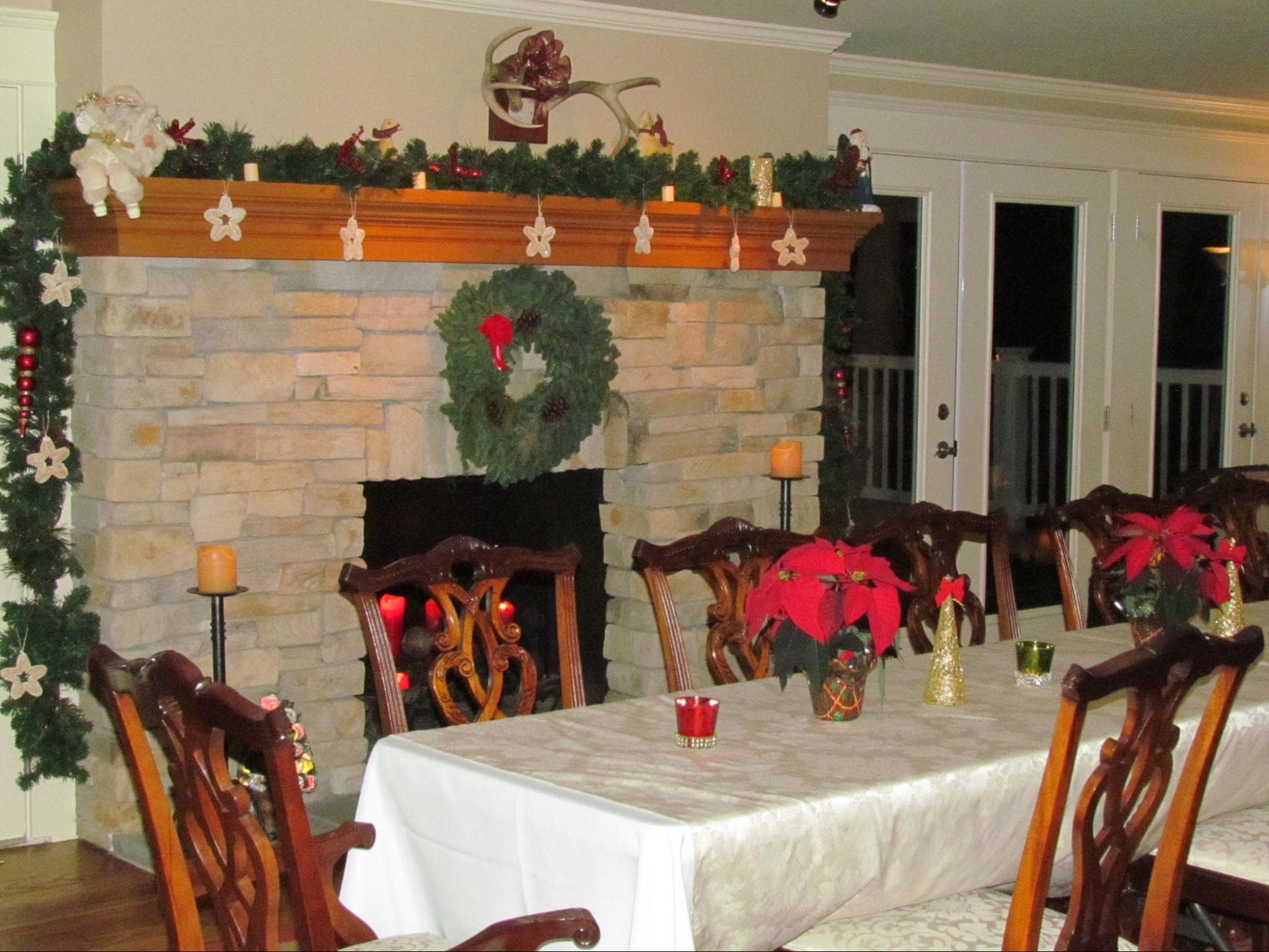 Cozy dining area decorated for the holidays with a stone fireplace and festive table settings.