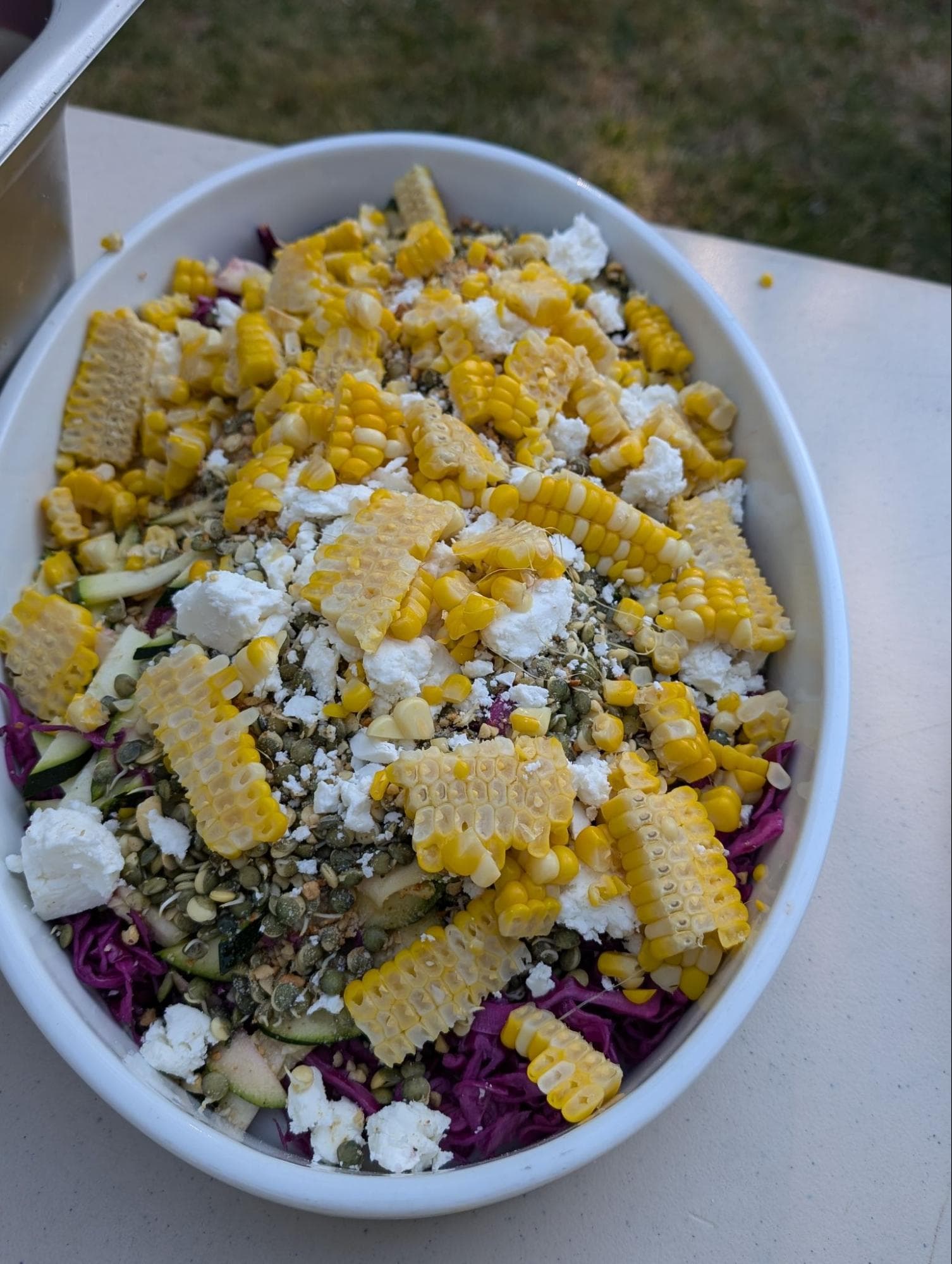 A colorful salad featuring purple cabbage, corn, feta cheese, and seeds.