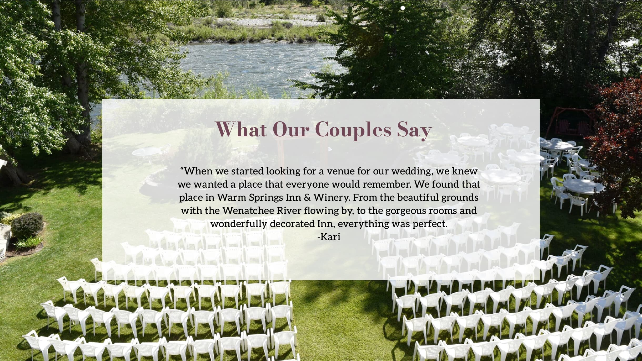 An outdoor wedding venue with white chairs set up on a lush lawn beside a river.