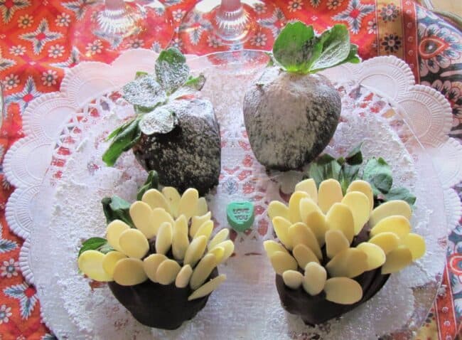 A decorative platter featuring chocolate-covered strawberries with white chocolate petals and a heart-shaped candy that says "Love You."