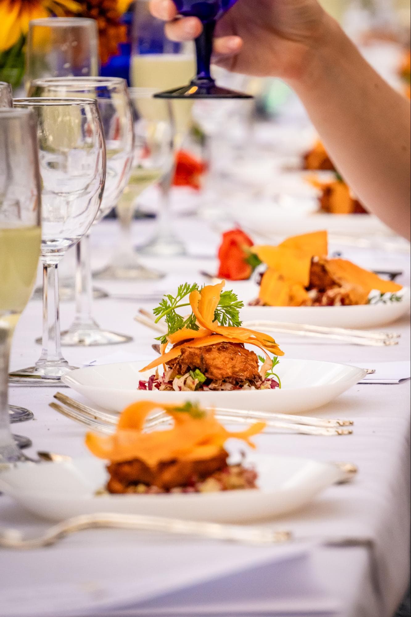 A beautifully arranged dinner table featuring plates of gourmet food and glasses of drinks.